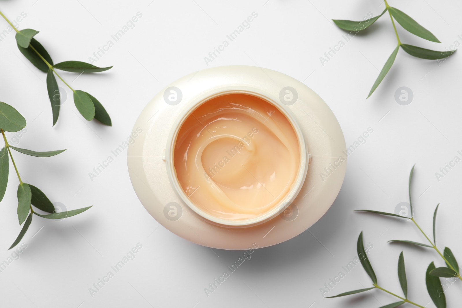 Photo of Jar of hair care cosmetic product and green leaves on white background, flat lay