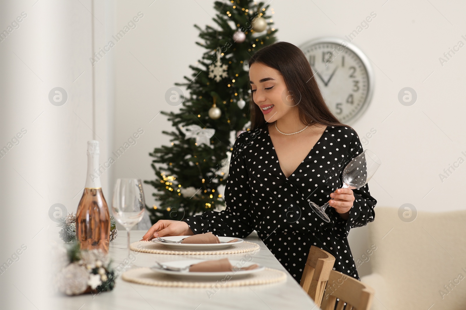 Photo of Happy woman serving table for Christmas in kitchen