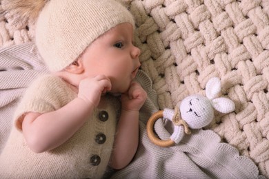 Cute newborn baby with toy bunny on beige crocheted plaid, top view