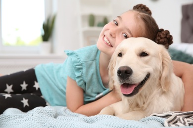 Cute little child with her pet on bed at home