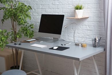 Photo of Interior of comfortable work place with computer on table at home