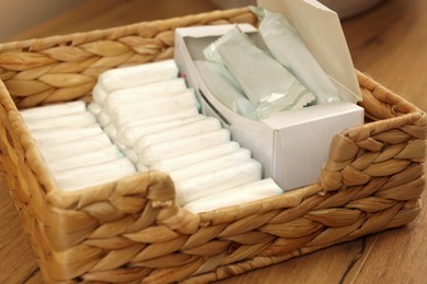 Many different tampons in wicker basket on wooden table, closeup. Menstrual hygienic product