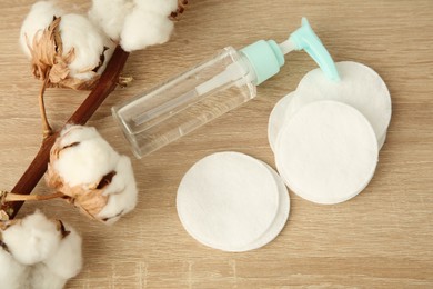 Photo of Cosmetic product, cotton pads and flowers on wooden table, above view