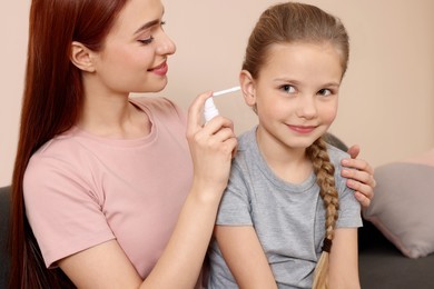 Mother spraying medication into daughter's ear in living room