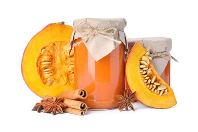 Photo of Jars of pumpkin jam, star anise, fresh pumpkin and cinnamon on white background