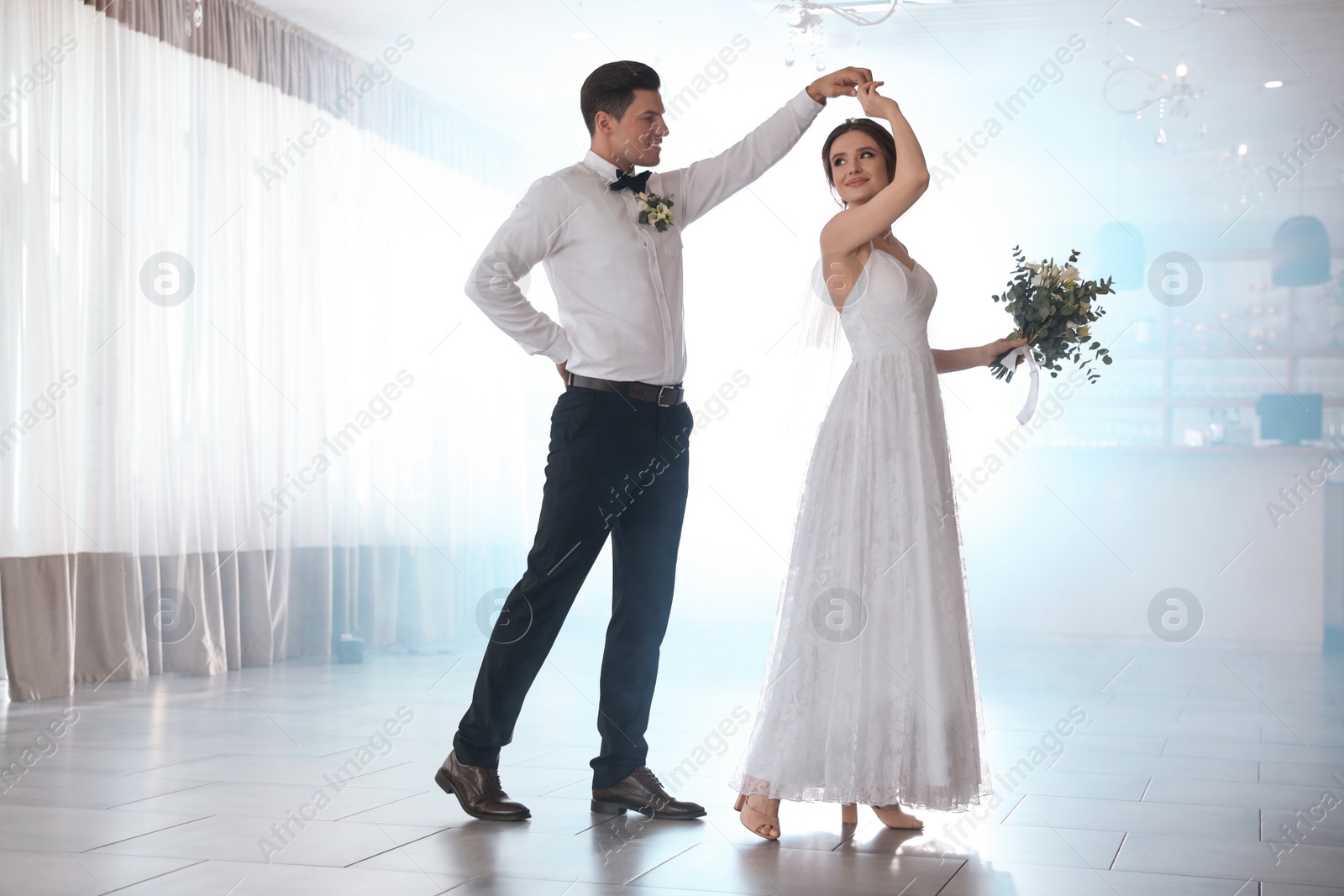 Photo of Happy newlywed couple dancing together in festive hall