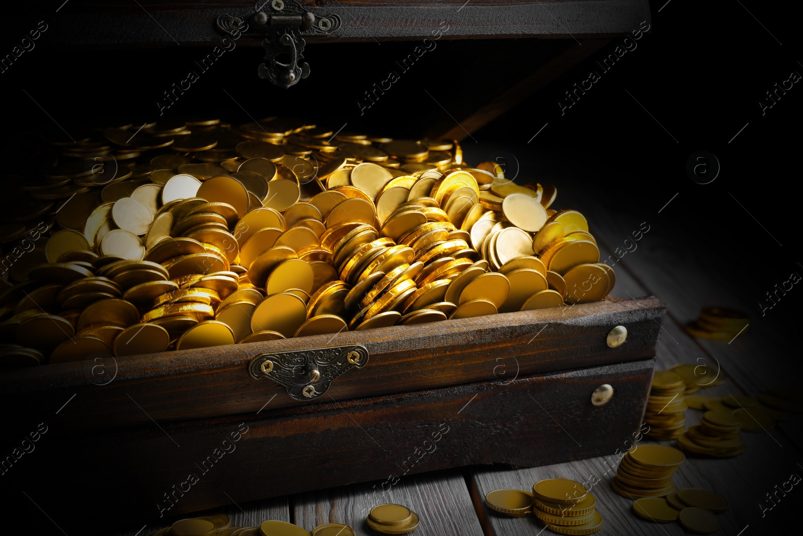 Image of Open treasure chest with gold coins on grey wooden table, closeup 