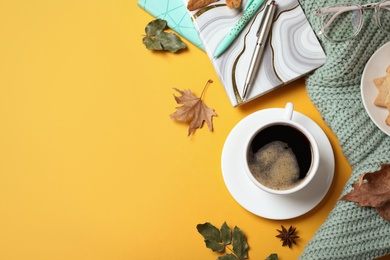 Photo of Flat lay composition with cup of hot drink on yellow background, space for text. Cozy autumn atmosphere