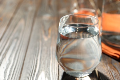 Photo of Glass of water on wooden table, closeup with space for text. Refreshing drink