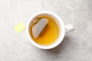 Photo of Brewing tea. Cup with tea bag on light table, top view