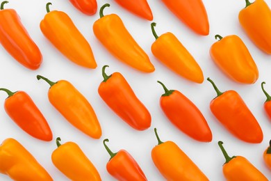 Many fresh raw orange hot chili peppers on white background, flat lay