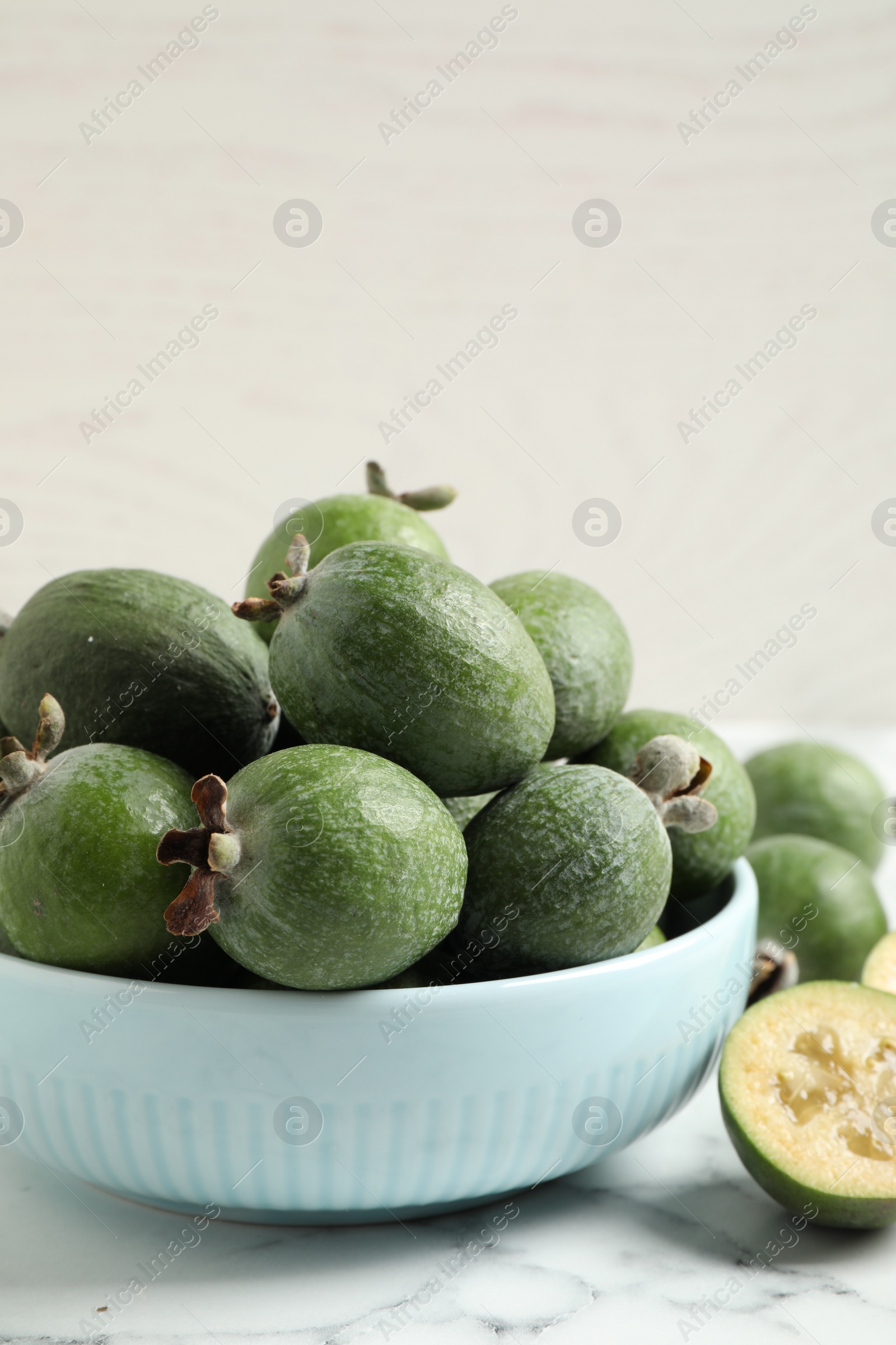 Photo of Fresh green feijoa fruits on white marble table, closeup