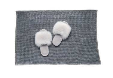 Photo of Soft grey bath mat and slippers isolated on white, top view