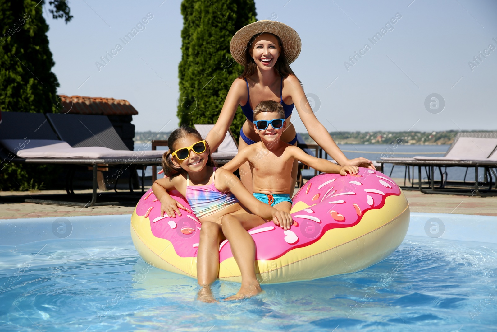 Photo of Woman with her children in swimming pool. Family vacation