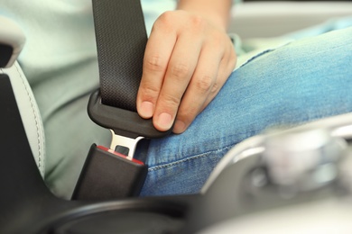 Male driver fastening safety belt in car, closeup