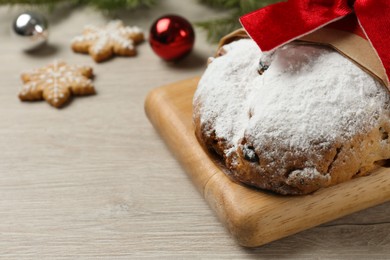 Photo of Wrapped Christmas Stollen on wooden table, closeup. Space for text