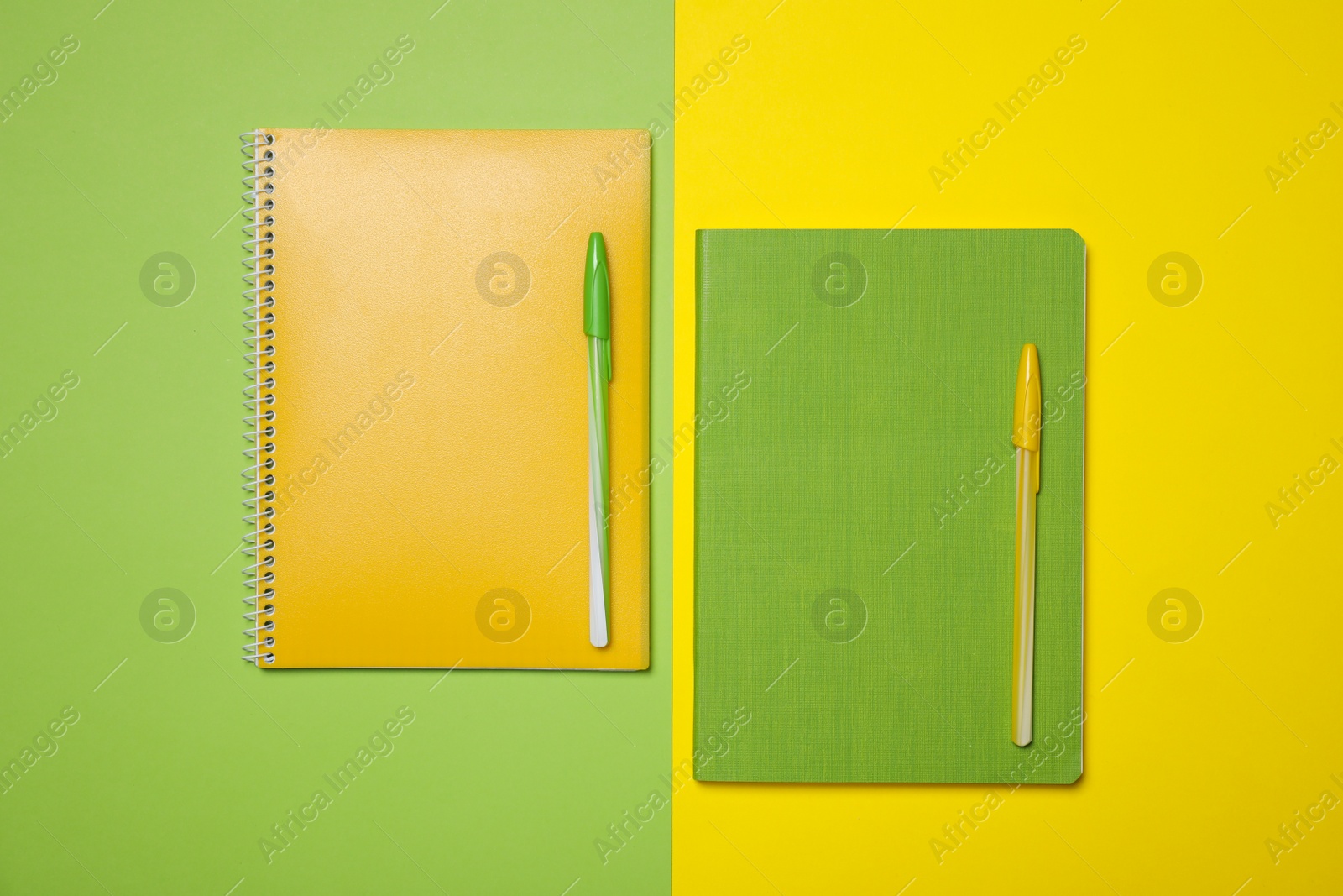 Photo of Notebooks and pens on color background, flat lay. School stationery