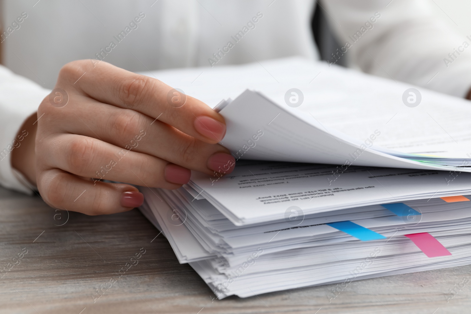 Photo of Woman reading documents at wooden table in office, closeup