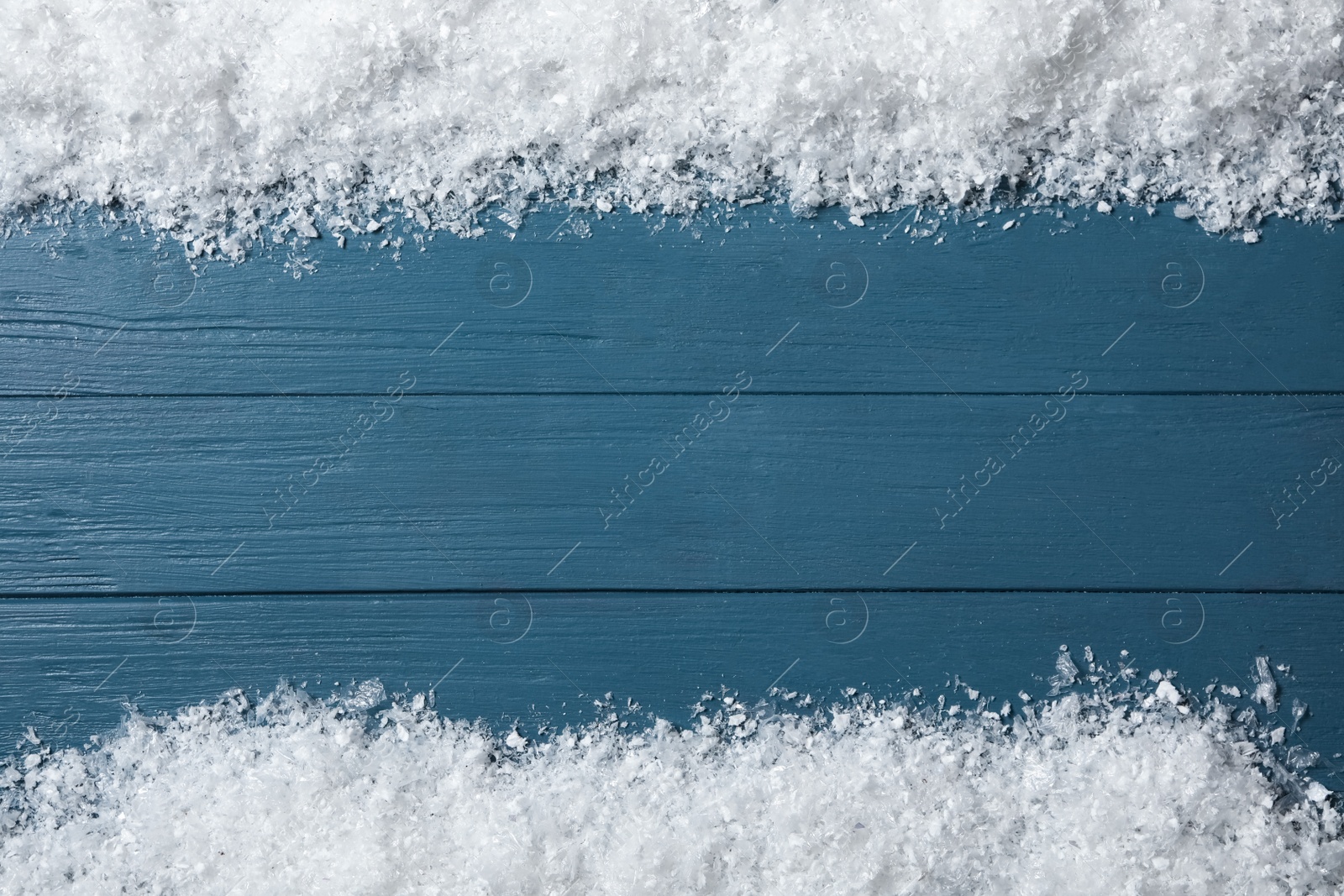 Photo of Frame made of snow on blue wooden background, top view with space for text. Christmas time