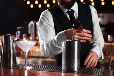 Bartender preparing fresh alcoholic cocktail at bar counter, closeup
