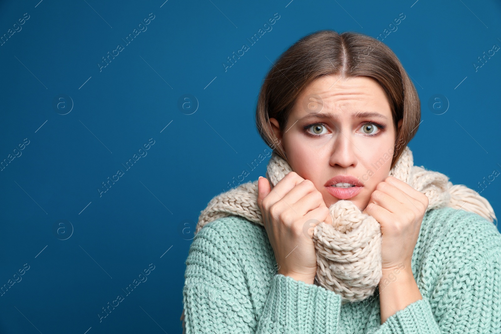 Image of Young woman wearing scarf suffering from fever on blue background, space for text. Cold symptoms