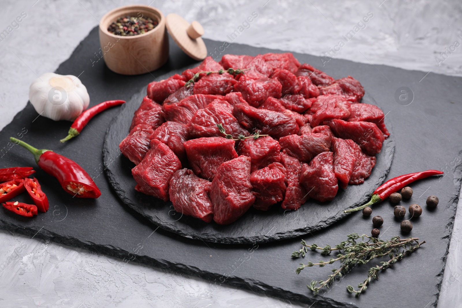 Photo of Pieces of raw beef meat, products and spices on grey textured table