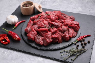 Photo of Pieces of raw beef meat, products and spices on grey textured table