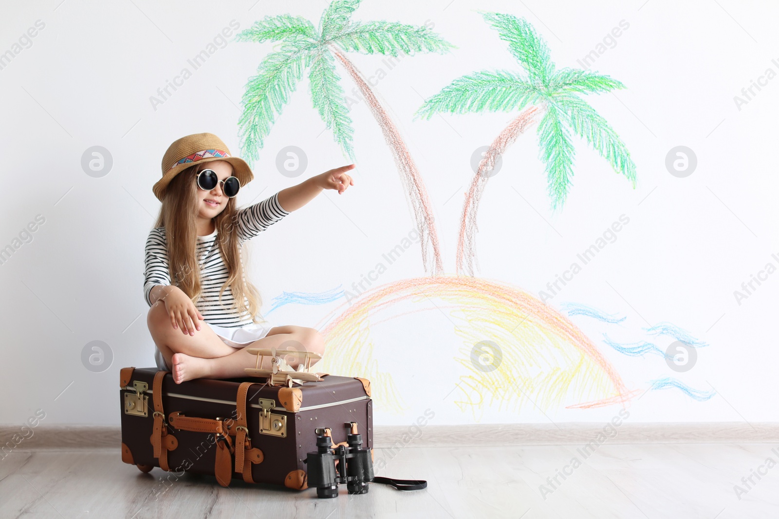 Photo of Adorable little child playing traveler with suitcase indoors