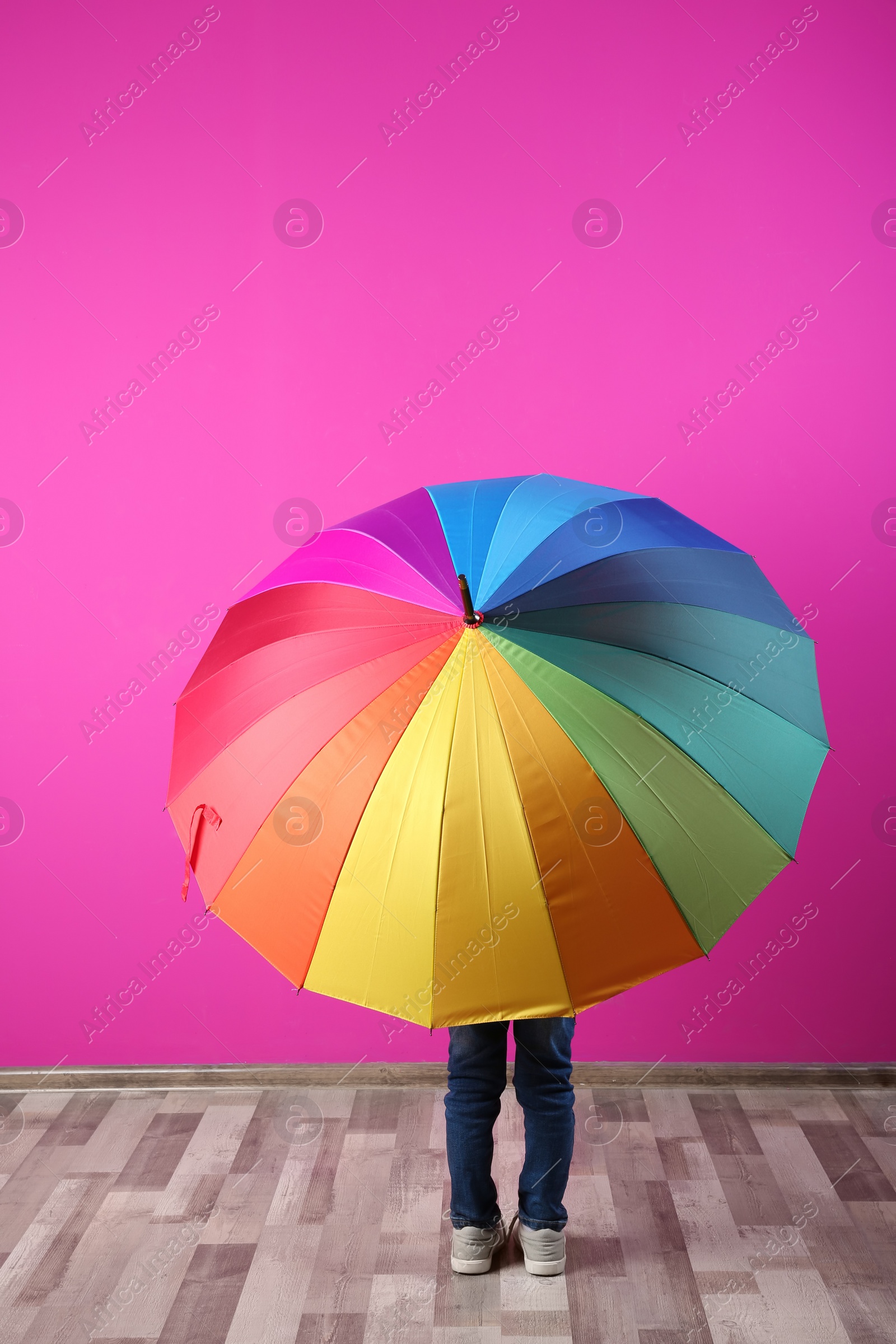 Photo of Little boy with rainbow umbrella near color wall