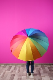 Photo of Little boy with rainbow umbrella near color wall