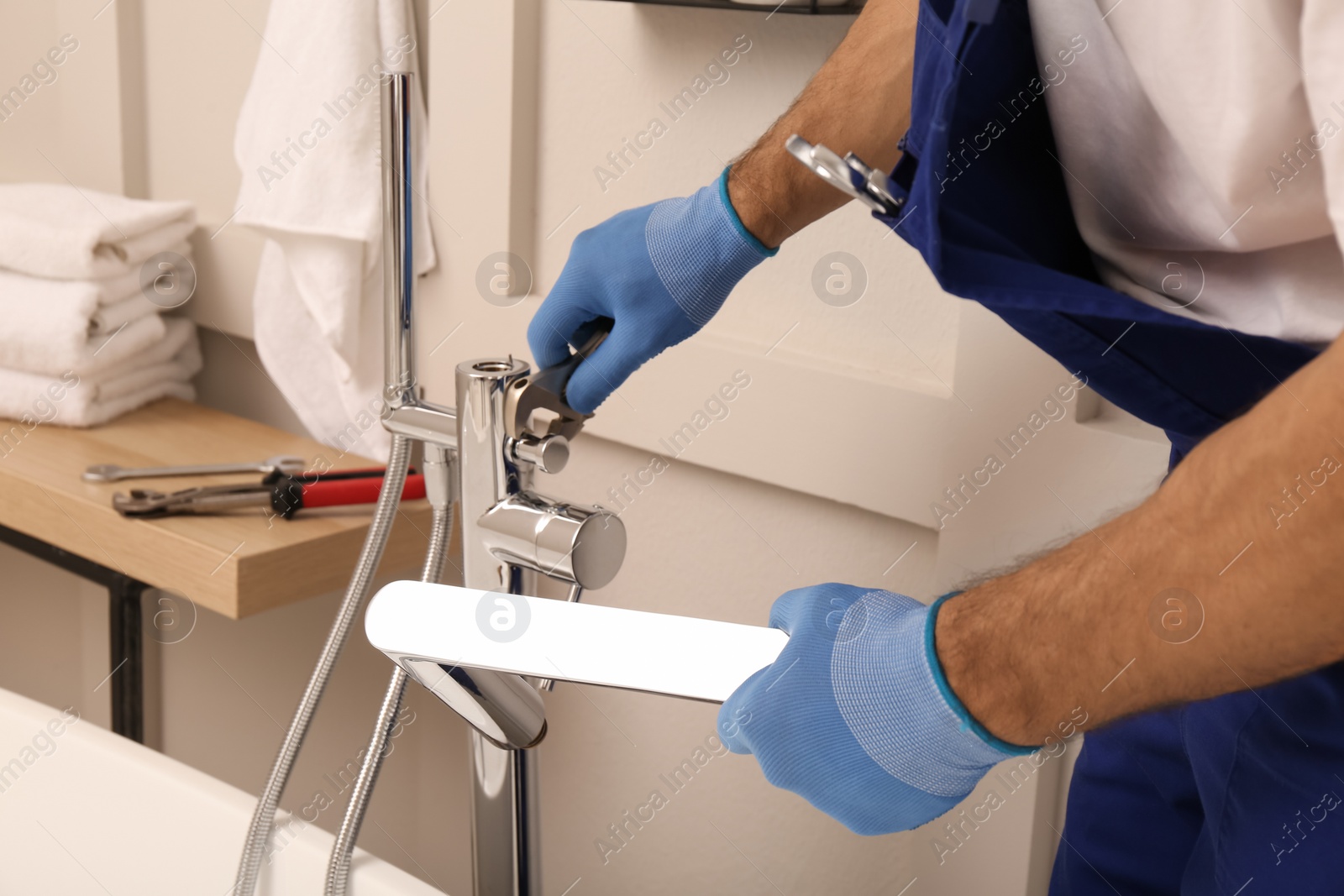 Photo of Professional plumber installing water tap in bathroom, closeup