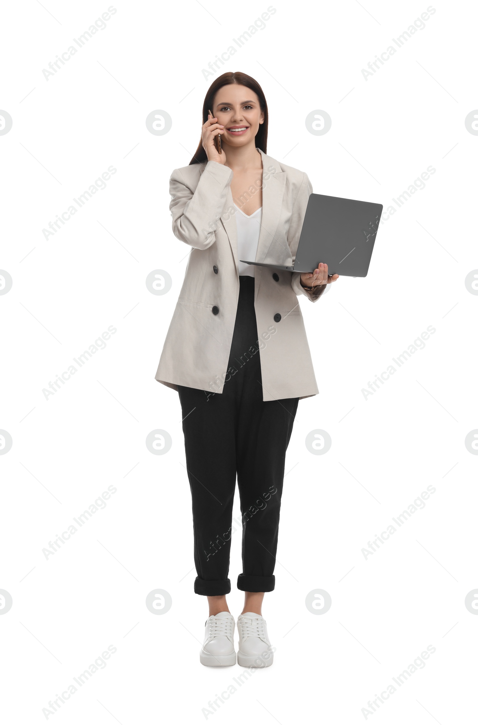 Photo of Beautiful businesswoman in suit with laptop talking on smartphone against white background