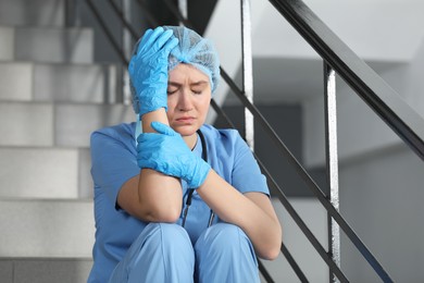 Exhausted doctor sitting on stairs in hospital