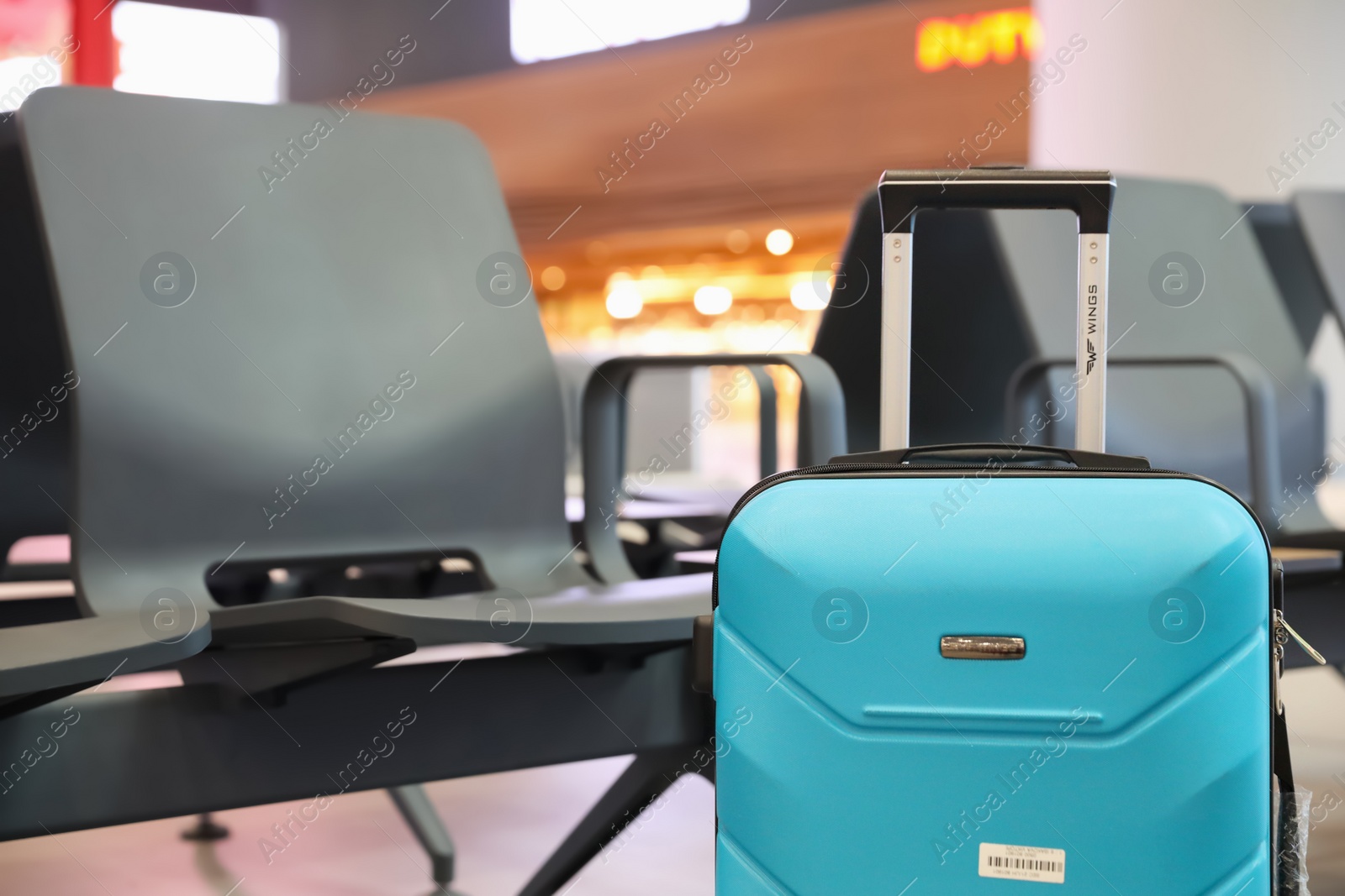 Photo of ISTANBUL, TURKEY - AUGUST 6, 2019: Bright modern suitcase near bench in airport