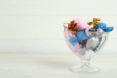 Photo of Candies in colorful wrappers on white wooden table, space for text