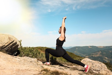 Image of Beautiful young woman practicing yoga in mountains on sunny morning