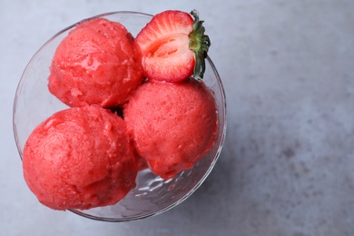 Photo of Delicious strawberry ice cream in dessert bowl on grey table, top view. Space for text