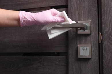 Woman wiping door handle with paper towel, closeup