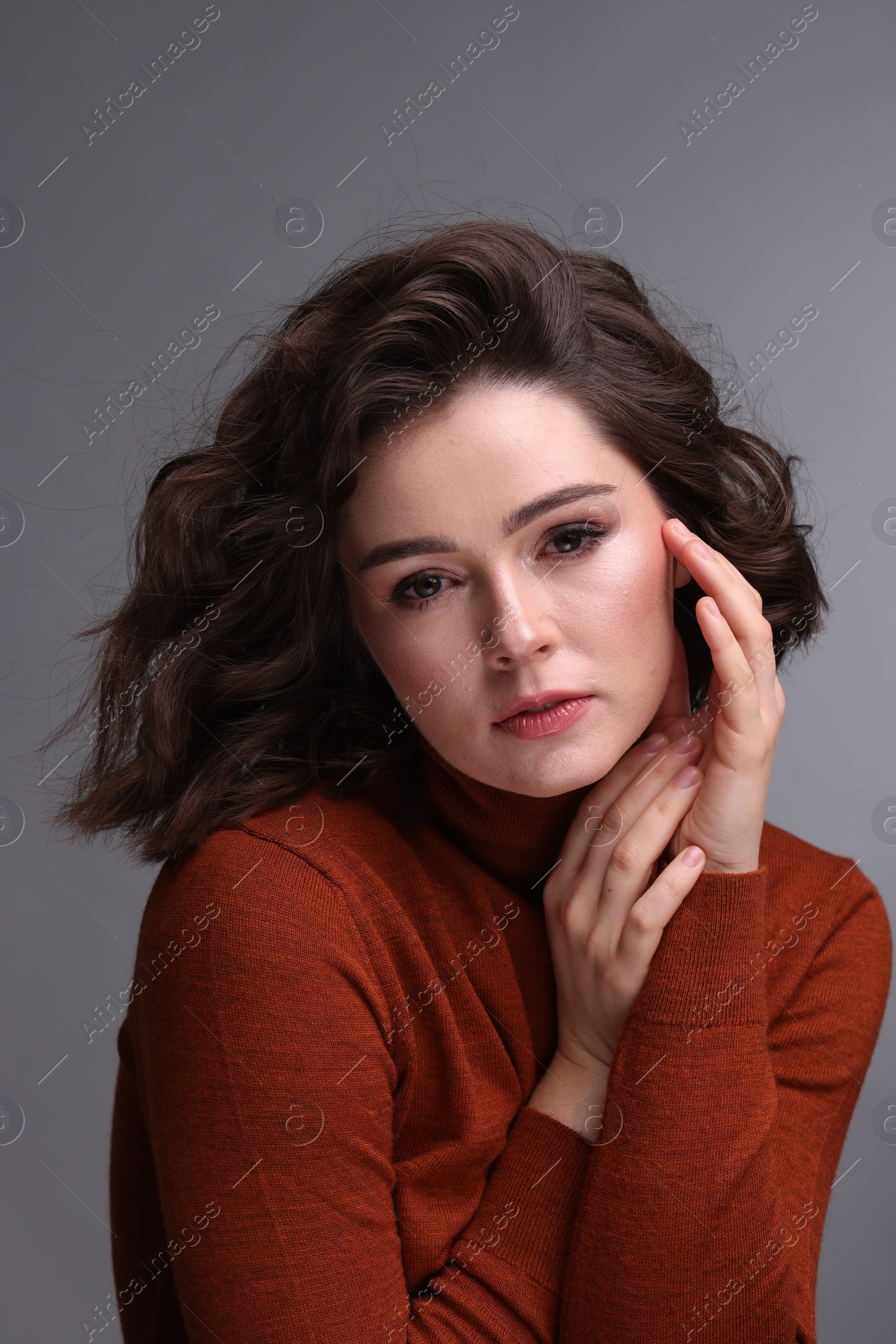 Photo of Portrait of beautiful young woman with wavy hairstyle on grey background