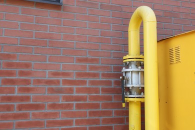 Yellow gas pipe near red brick wall outdoors, space for text