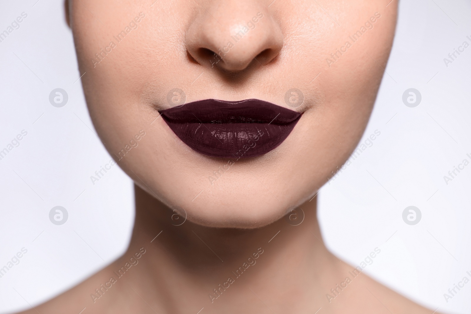 Photo of Young woman with beautiful lips makeup on light background, closeup