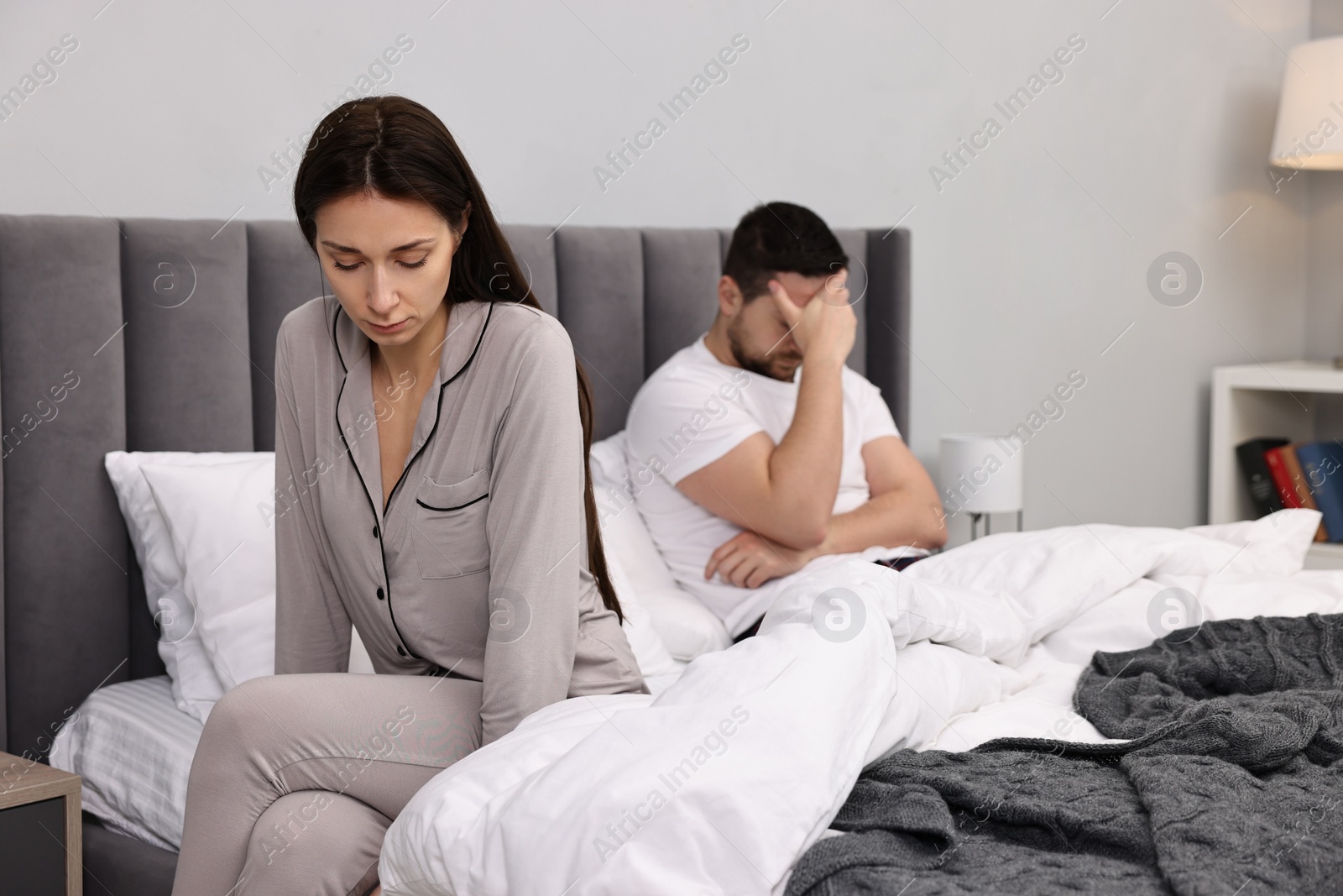 Photo of Offended couple ignoring each other after quarrel in bedroom, selective focus. Relationship problems