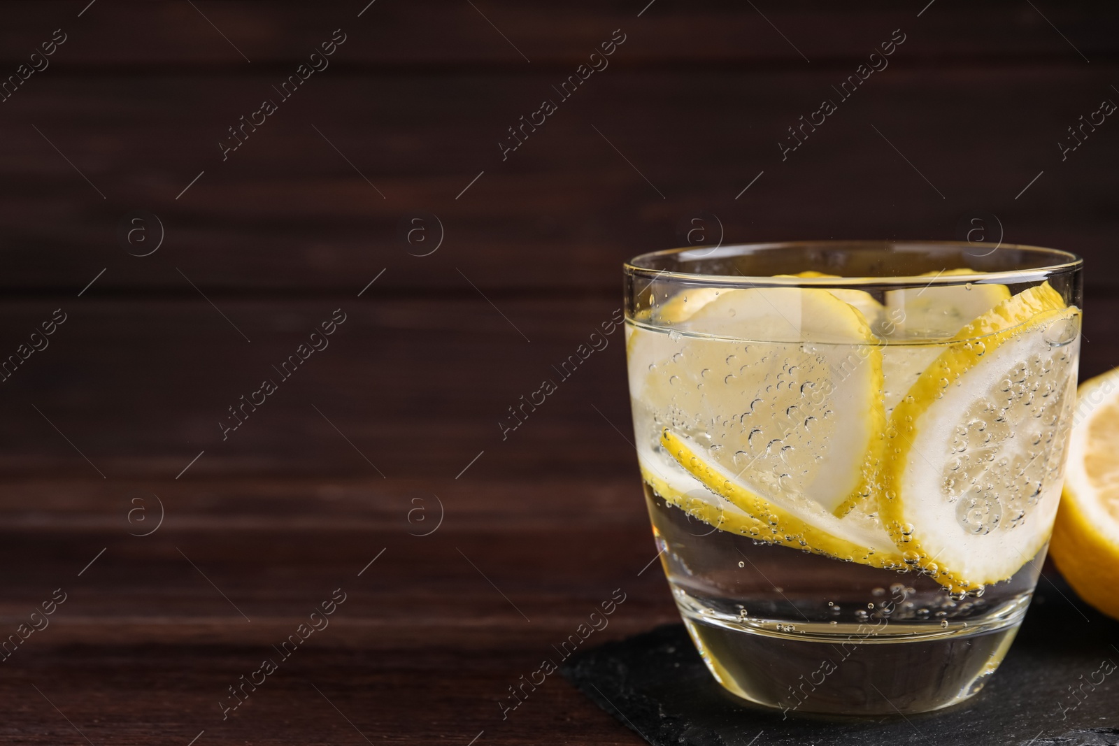 Photo of Soda water with lemon slices on wooden table. Space for text