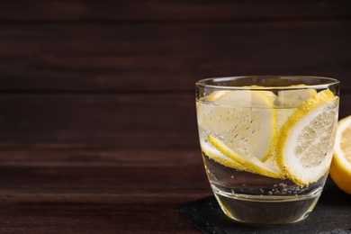 Photo of Soda water with lemon slices on wooden table. Space for text