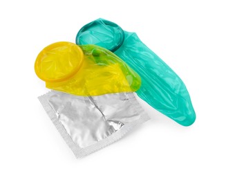 Photo of Unrolled condoms and package on white background. Safe sex