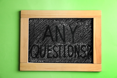 Photo of Blackboard with words ANY QUESTIONS on green background, top view