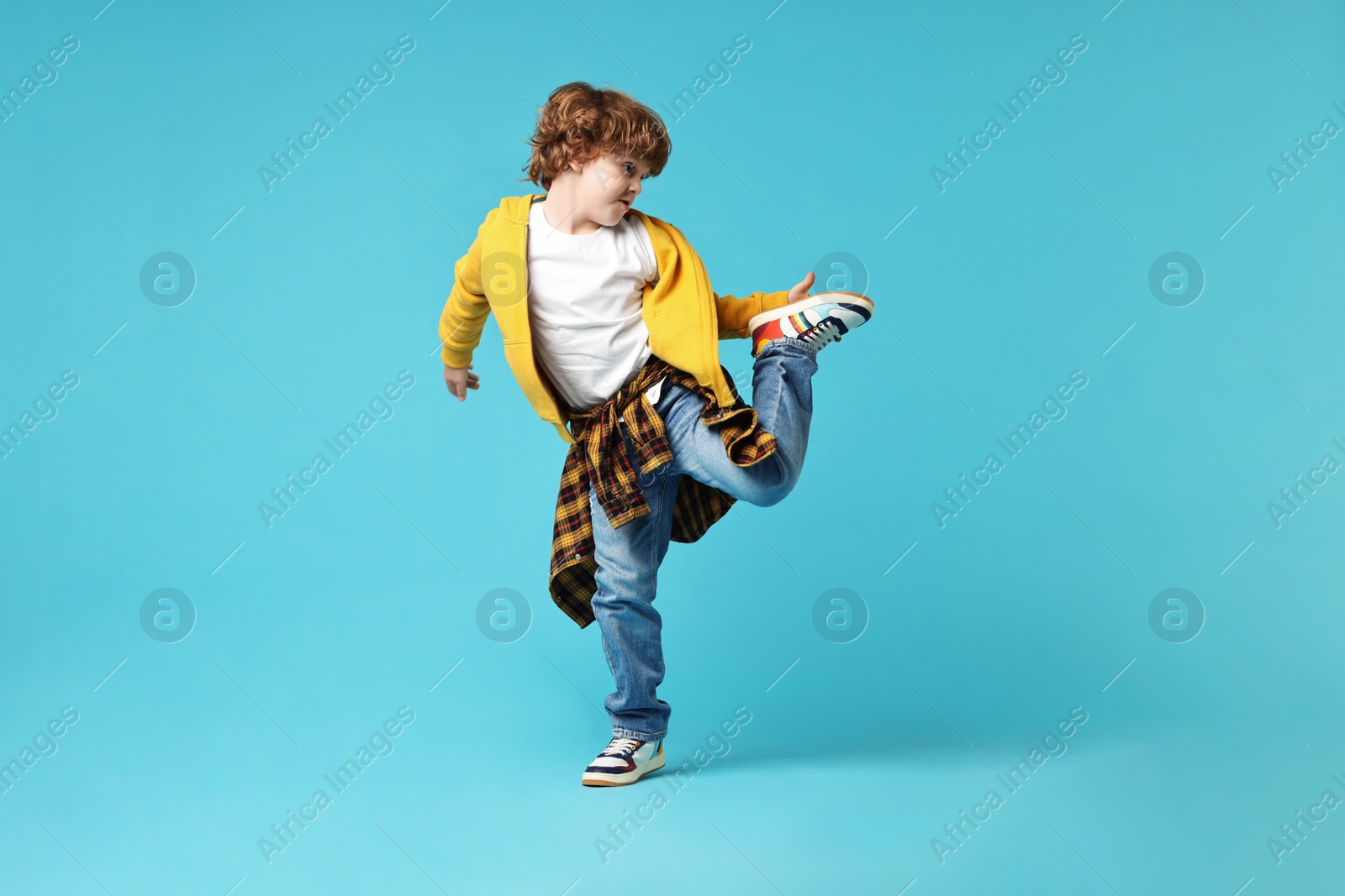 Photo of Happy little boy dancing on light blue background