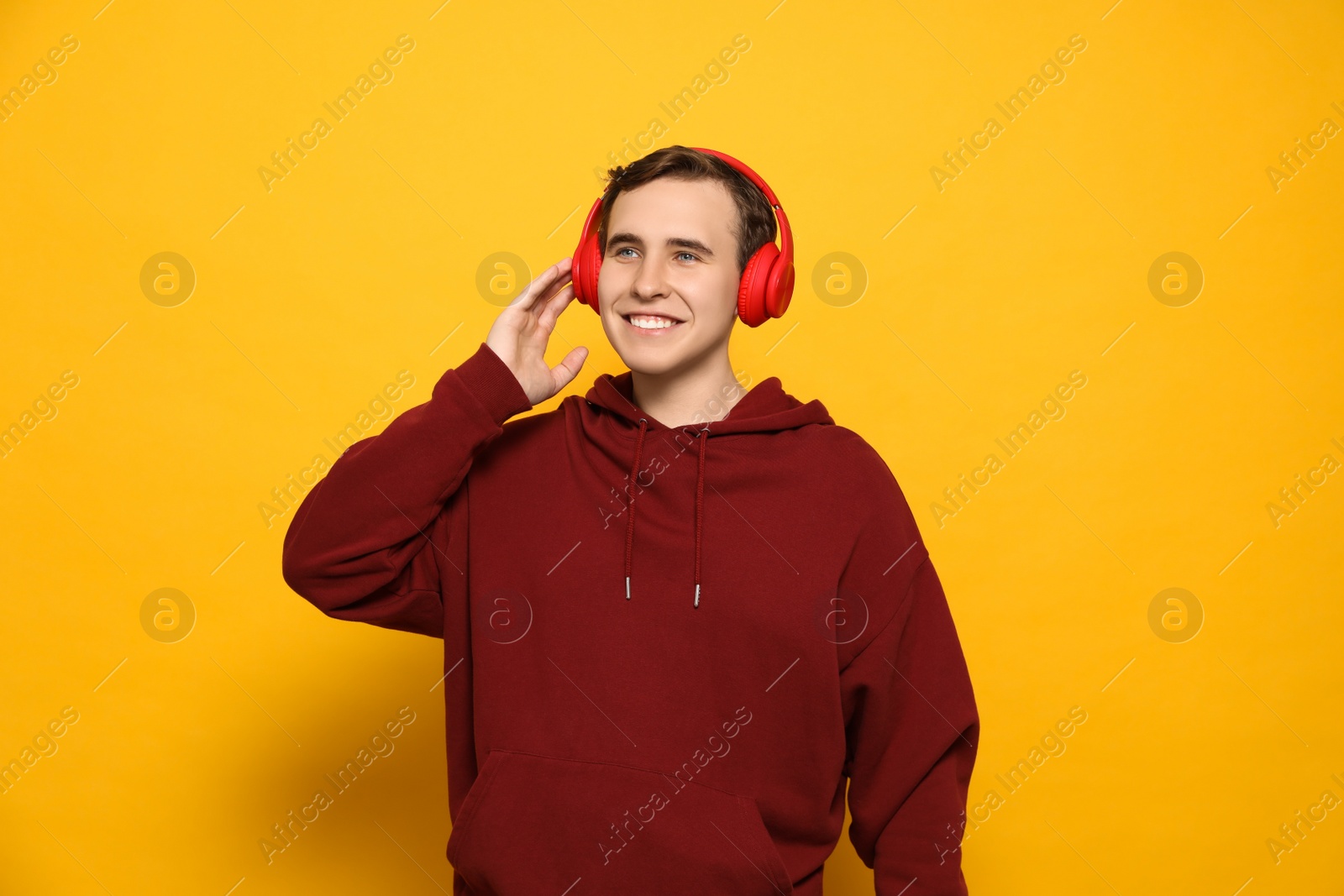 Photo of Handsome young man with headphones on yellow background