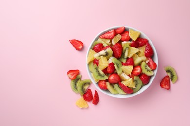 Yummy fruit salad in bowl and ingredients on pink background,flat lay. Space for text