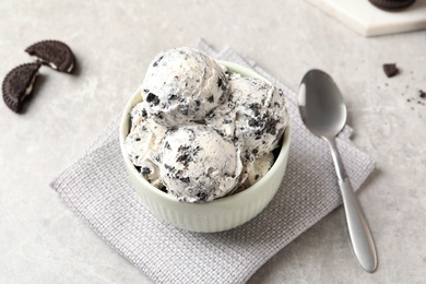 Photo of Bowl with ice cream and crumbled chocolate cookies on grey background